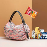 Pink camo foldable shopping bags set with black handles holding groceries including snacks coffee and blueberries