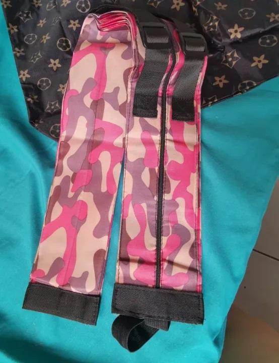 Pink camo foldable shopping bags set with black straps folded on a teal fabric background