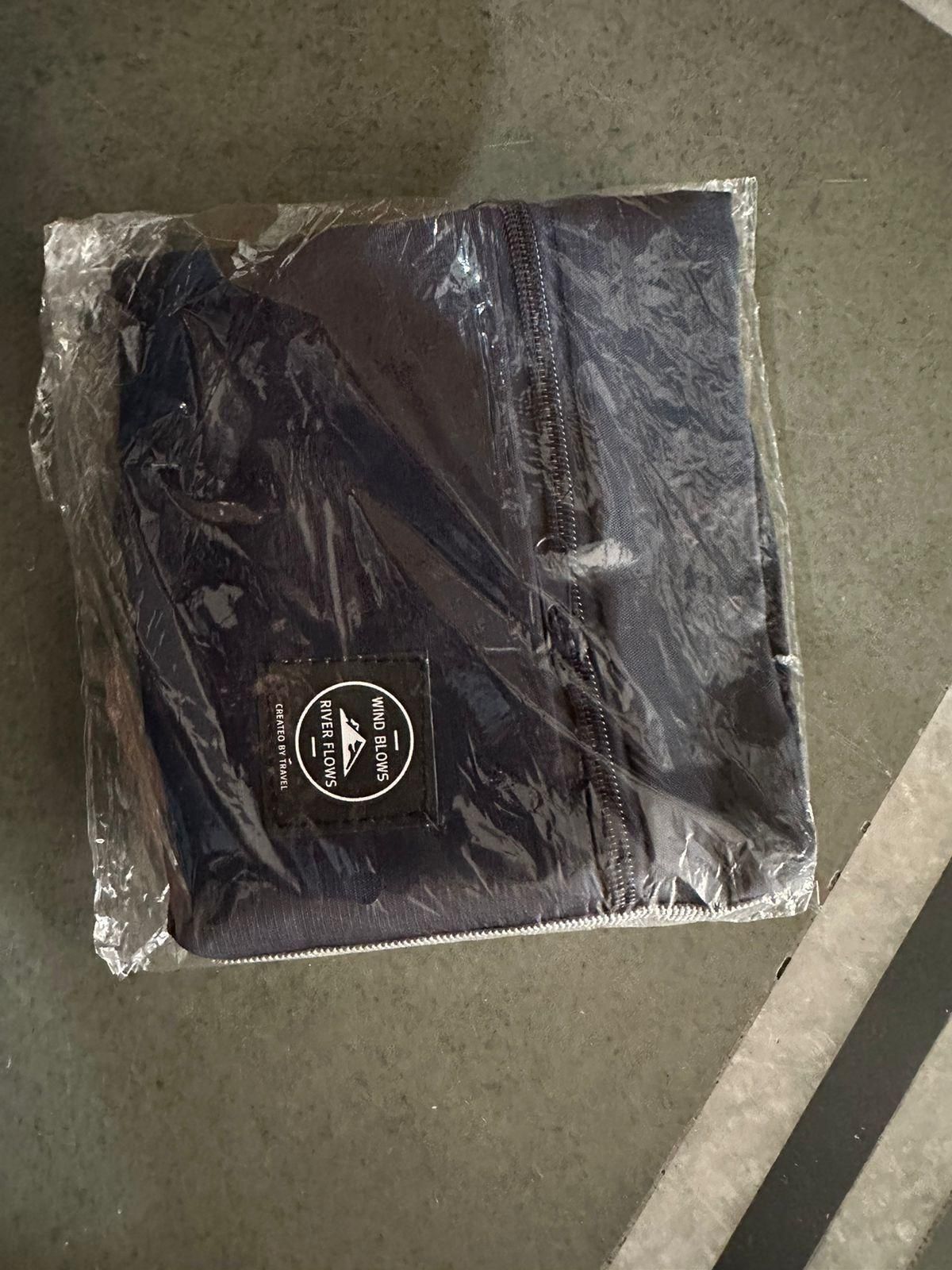 Folded black carry on duffel bag for women wrapped in clear plastic packaging
