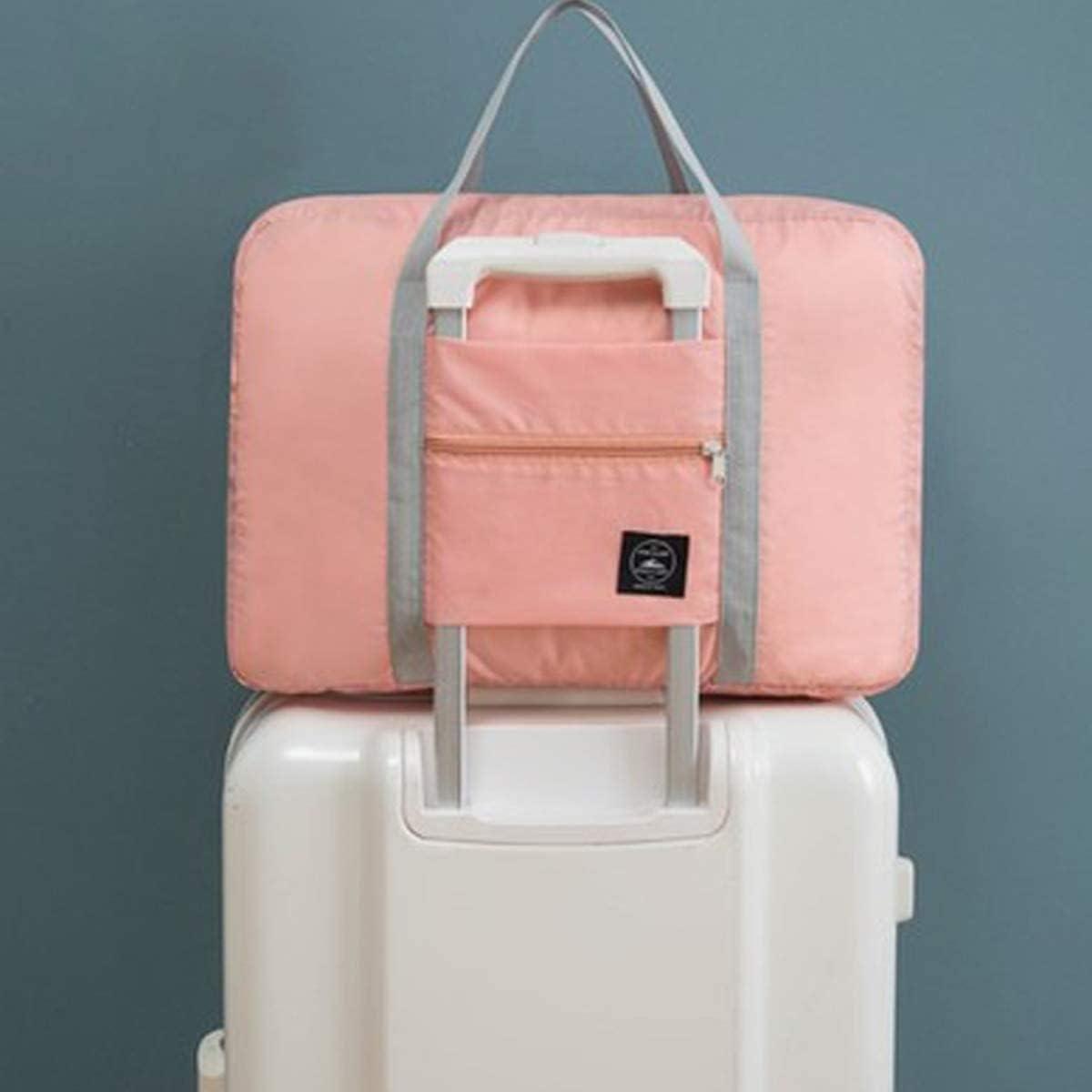 Pink carry on duffel bag for women with gray handles placed on top of white suitcase