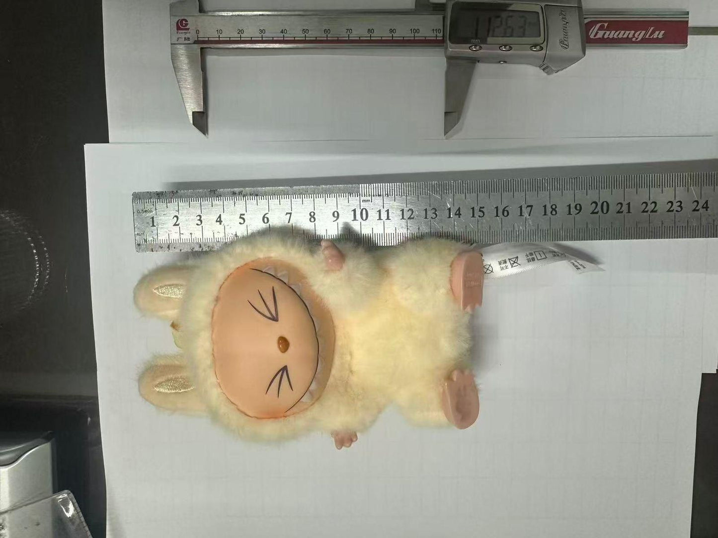 Labubu doll online India fluffy beige toy with bunny ears lying next to ruler showing size