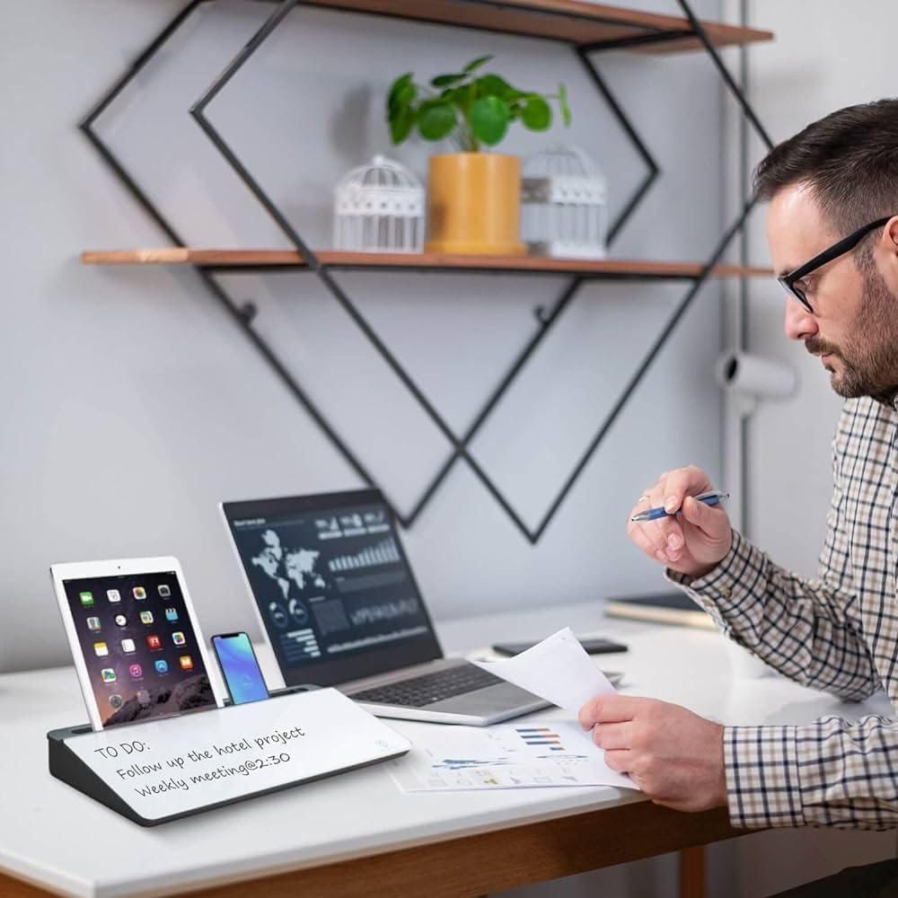 Man working at a desk with a multifunctional storage desk board holding tablet phone and notes