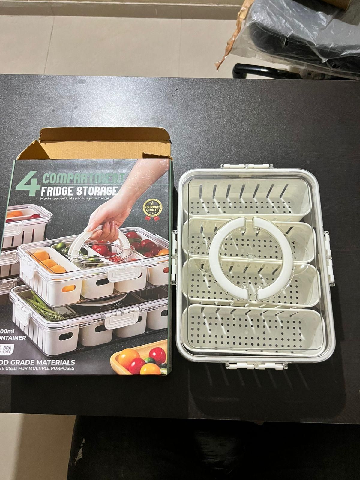 White plastic fridge storage container with compartments and a box showing four stackable fridge storage containers