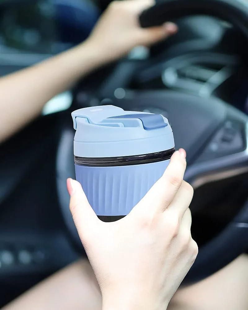 Eco friendly glass tumbler India in blue with lid held by person inside a car