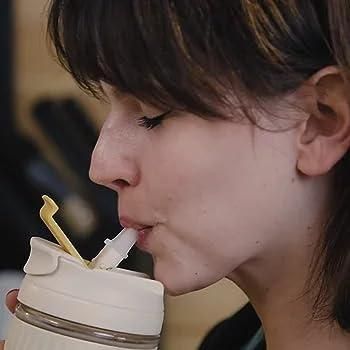 Woman drinking from an eco friendly glass tumbler India with a reusable straw and secure lid