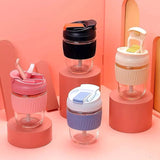 Set of colorful eco friendly glass tumbler India drinkware with silicone lids and straws on pink display