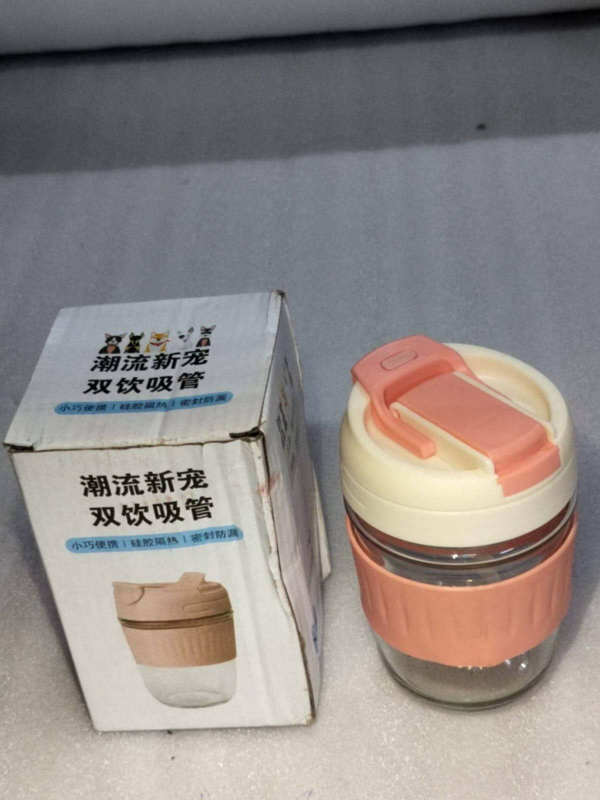 Eco friendly glass tumbler India with peach and cream lid and silicone grip next to its packaging box