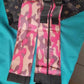 Pink camo foldable shopping bags set with black straps folded on a teal fabric background