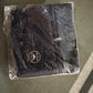 Folded black carry on duffel bag for women wrapped in clear plastic packaging