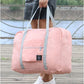 Light pink carry on duffel bag for women with gray straps held by a person wearing white perforated sneakers