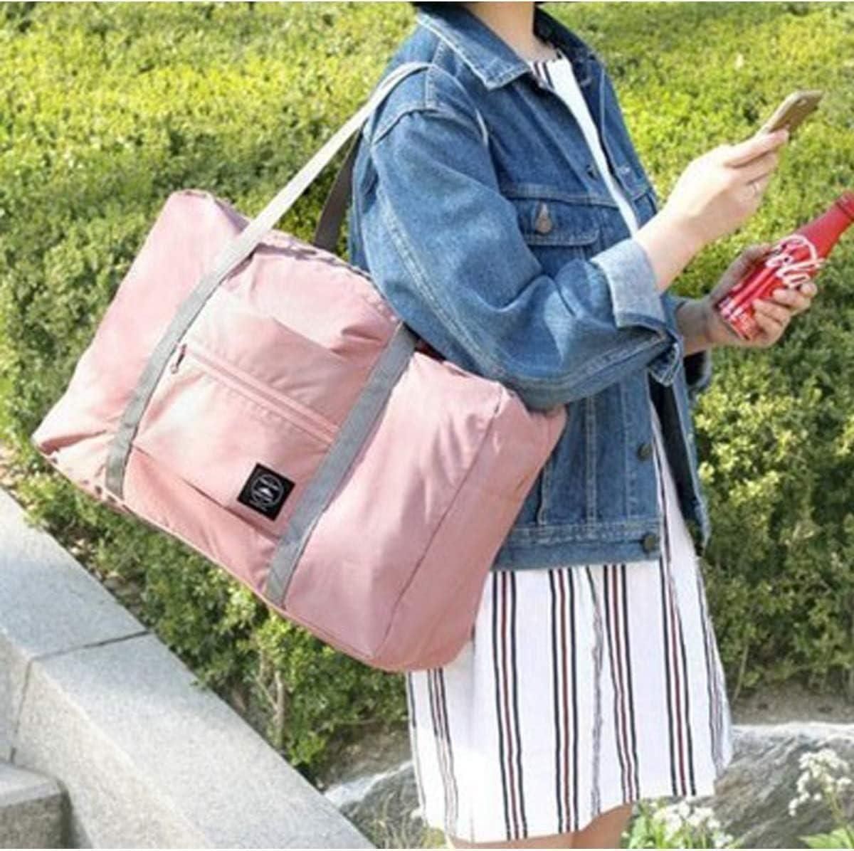 Pink carry on duffel bag for women with gray straps worn over shoulder by woman in denim jacket