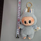 Labubu doll online India gray plush keychain with big eyes and bunny ears next to measuring tape