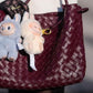 Two small Labubu dolls hanging from a maroon woven handbag in Labubu doll online India