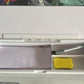 White multifunctional storage desk board with compartments holding papers, pen, and small yellow item for office organization