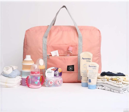 Pink portable travel organizer India with gray handles surrounded by baby care items and clothes