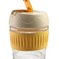 Eco friendly glass tumbler India with beige lid and yellow silicone grip for easy drinking